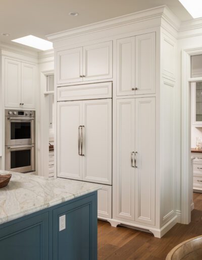 A kitchen with white cabinets and a blue island.