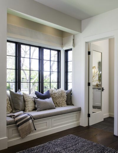 A room with a window seat and a rug.